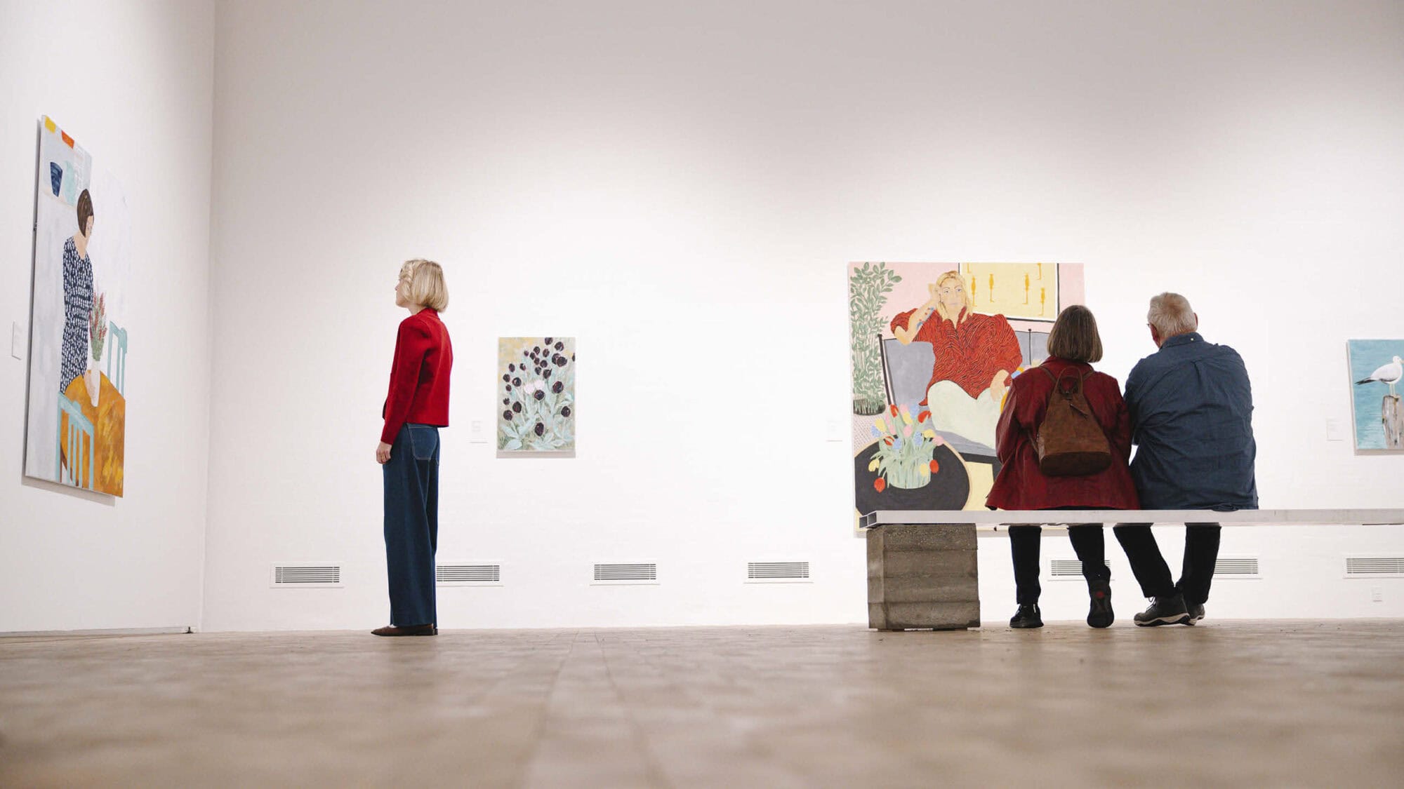 Tre personer som kigger på Anette Abrahamssons værker i kunstudstillingen Female Muses