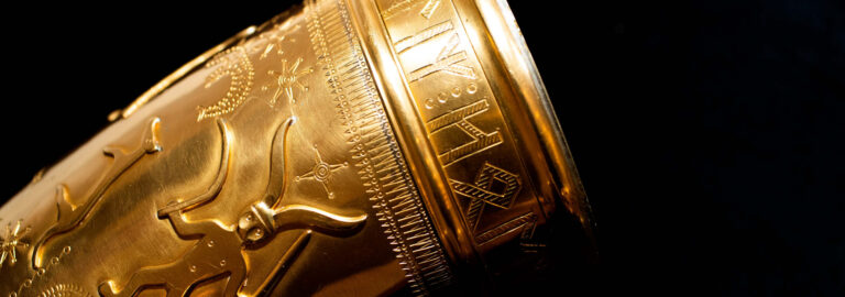 Udsnit af et horn i guld med udsmykning.