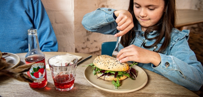 Pige sidder med en sandwich.