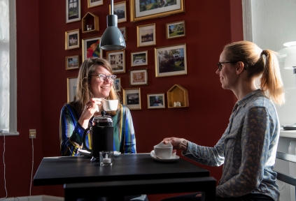 To kvinder sidder og drikker kaffe i caféen på Brundlund Slot