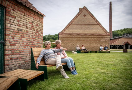 Two women are taking a break on a bench by Cathrinesminde Brickworks