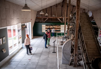 Ein paar Leute betrachten die Ziegeleimaschine und die Ziegel in der Ausstellung bei der Ziegelei Cathrinesminde