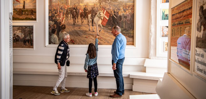 A couple and a child are looking at a painting in Sønderborg Castle