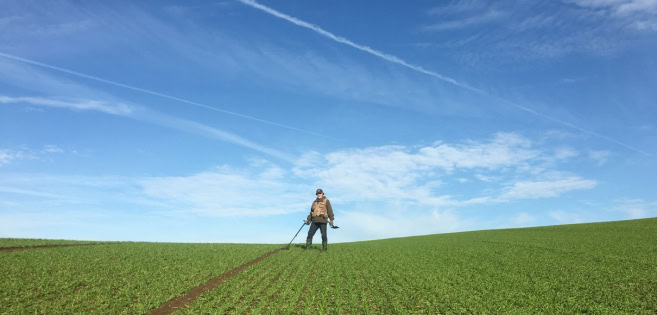 Ein Mann ist mit einem Metalldetektor auf einem Feld unterwegs