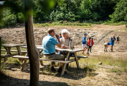 A couple is enjoying a break at the clay pit, while some people search for fossils in the background