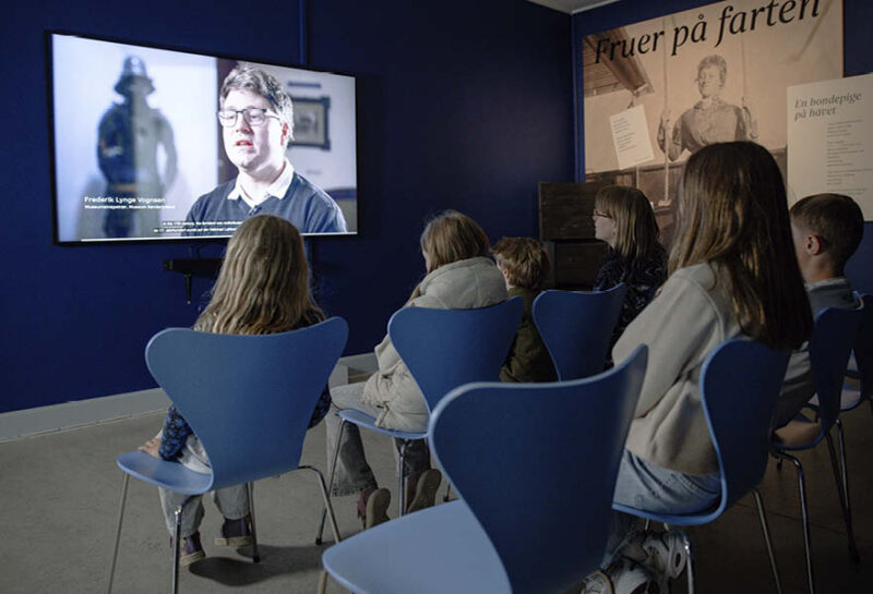 Personer sidder og ser en film om søfartens historie på Kulturhistorie Aabenraa