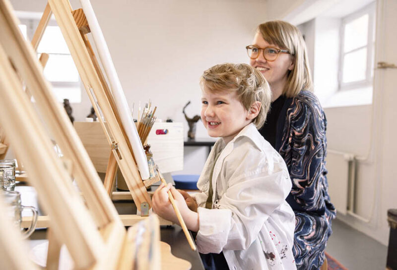 Dreng og hans mor sidder og maler