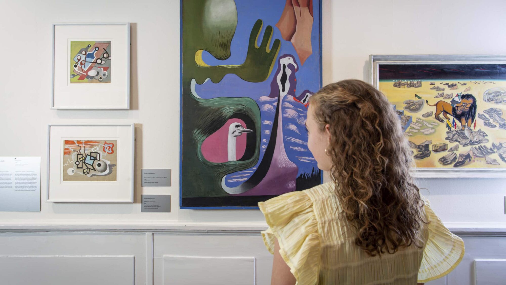 Kvinde står foran fire malerier i udstillingen Franciska Clausen og det underste land på Kunstmuseet Brundlund Sloot